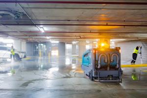 Professional car park cleaning service with high-pressure jetting equipment and workers in safety vests