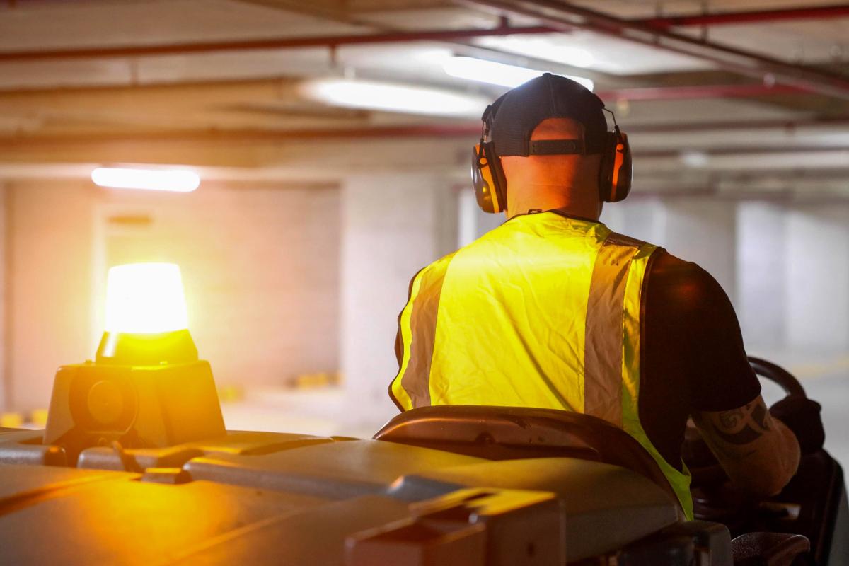 Worker in yellow safety vest and protective gear conducting industrial site inspection