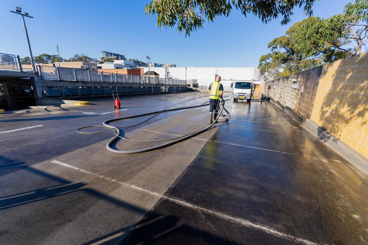 Professional high-pressure cleaning of a commercial car park surface with cleaning equipment and operators