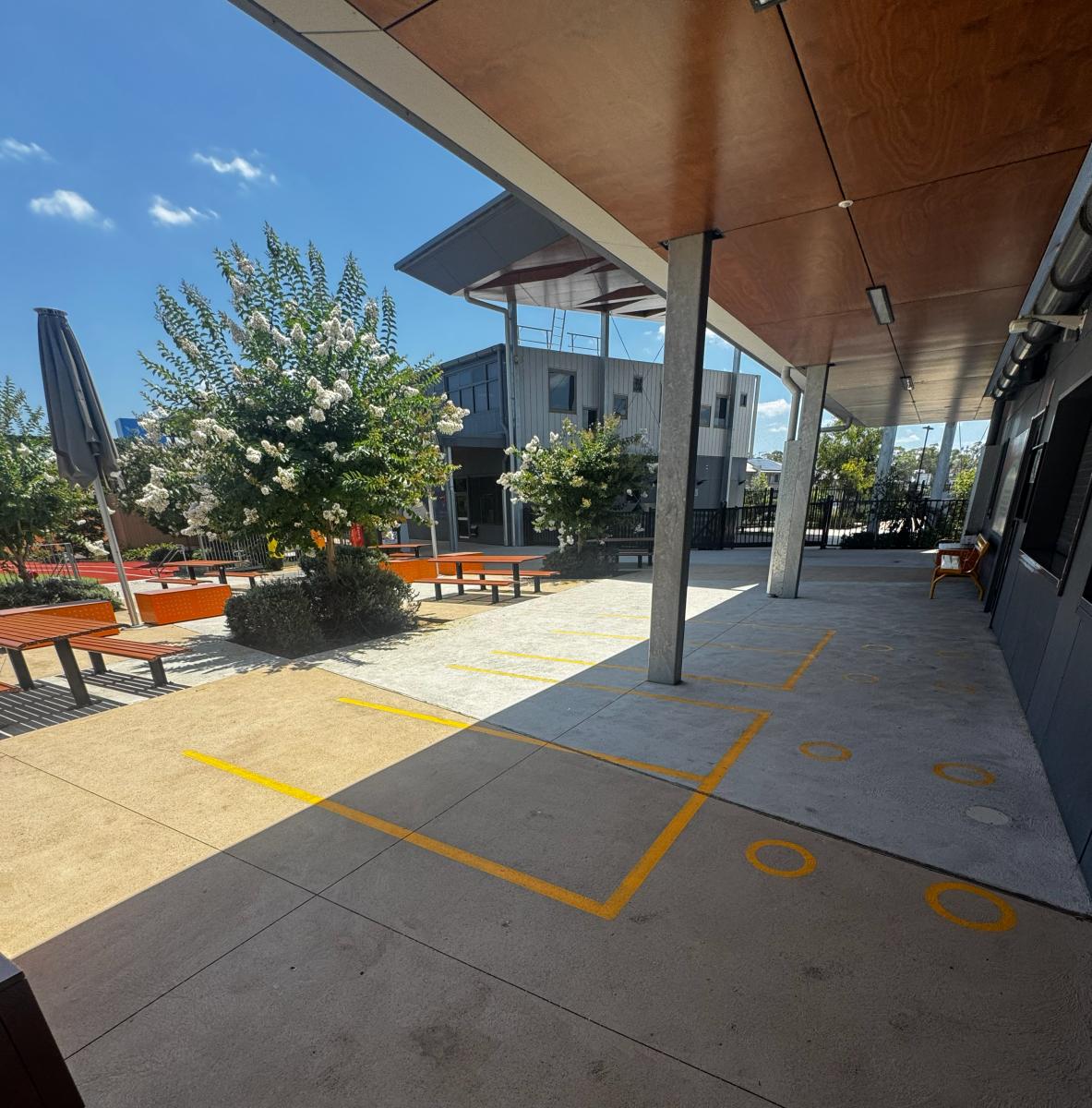 Modern car park entrance with clean paved surface, yellow line markings, and covered parking structure