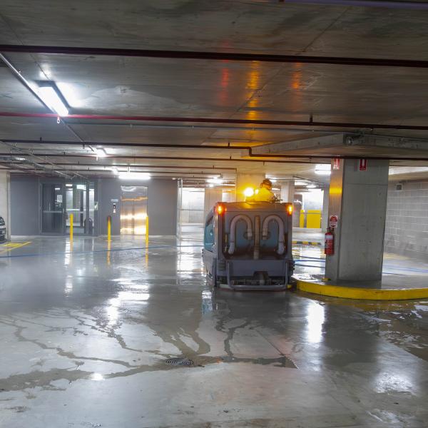 Underground car park with yellow safety bollards and professional floor cleaning maintenance