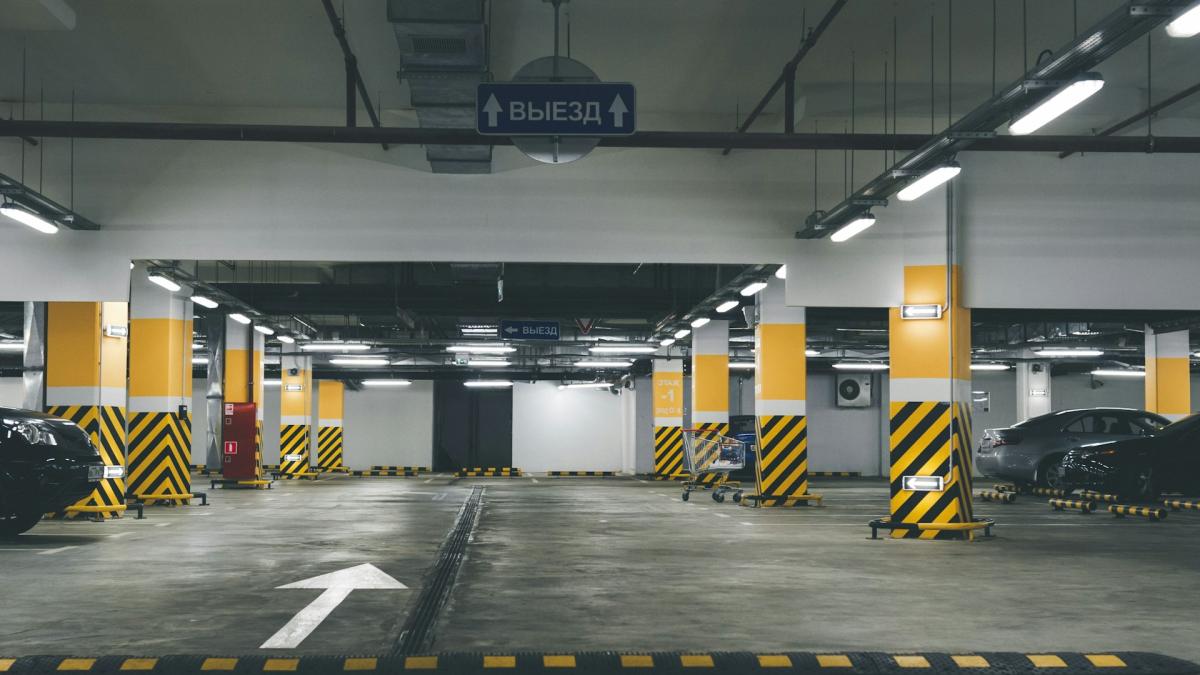 Empty underground car park with yellow and black safety pillars and directional signage