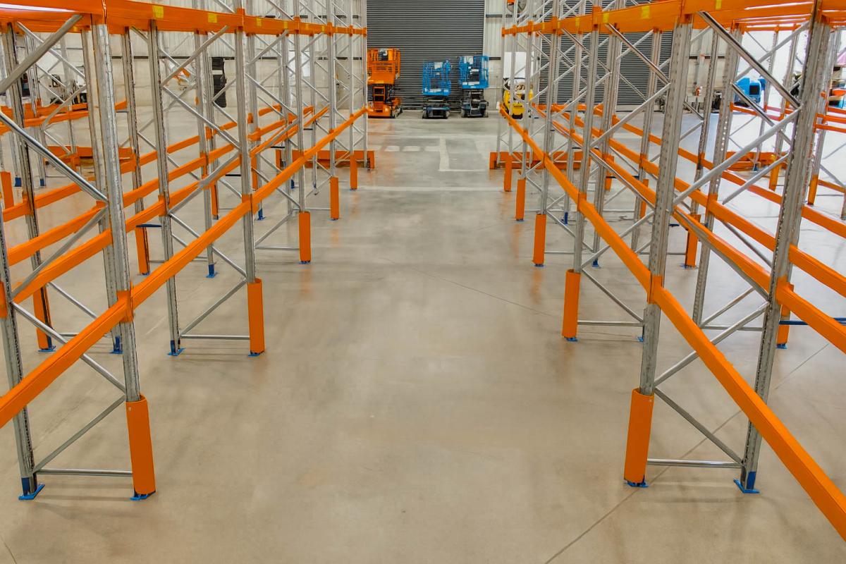 Clean warehouse floor with orange racking system and industrial equipment in background