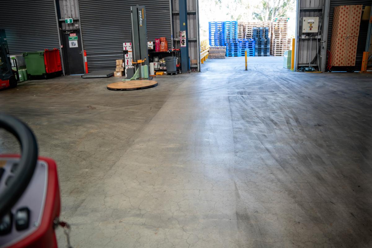 Large warehouse facility floor with industrial storage pallets and cleaning in progress