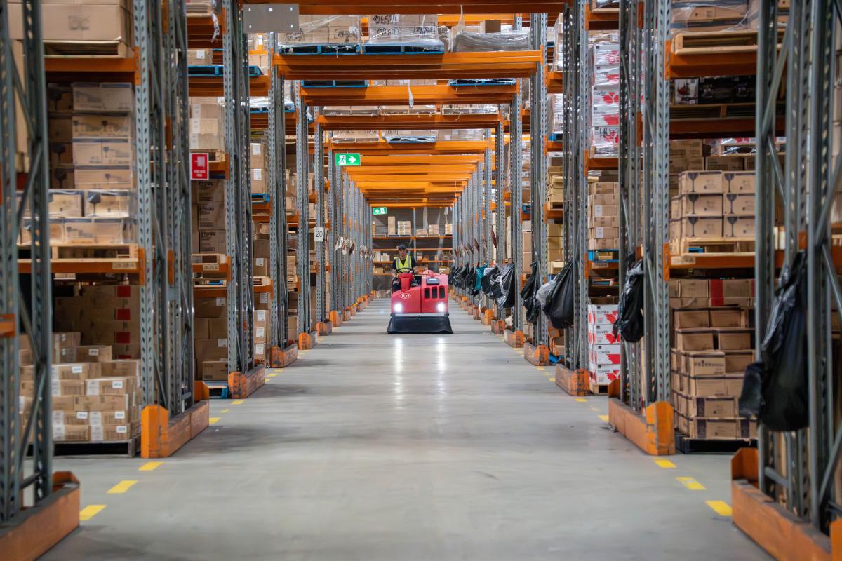 Warehouse aisle with industrial cleaning equipment and organised stock shelving